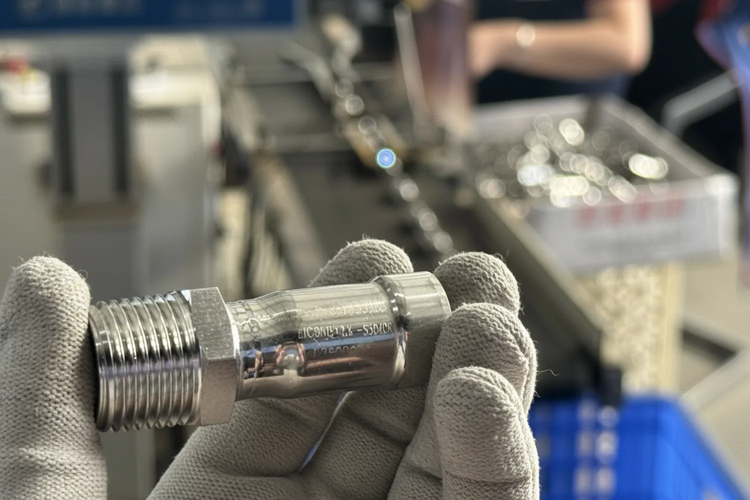Worker inspecting stainless steel pipe fittings with laser-etched traceability code on production line