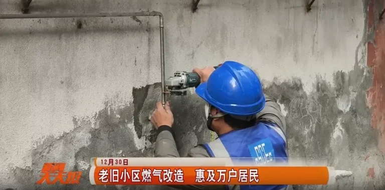 A worker precisely measures and cuts a stainless steel pipe to size at the residential retrofit worksite.
